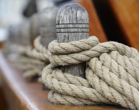 A selective focus shot of a wooden bollard with a tied rope