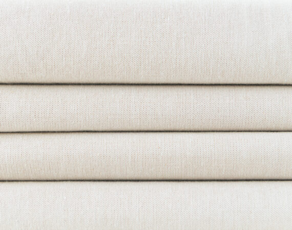 Stack of folded beige woven fabric patterned background